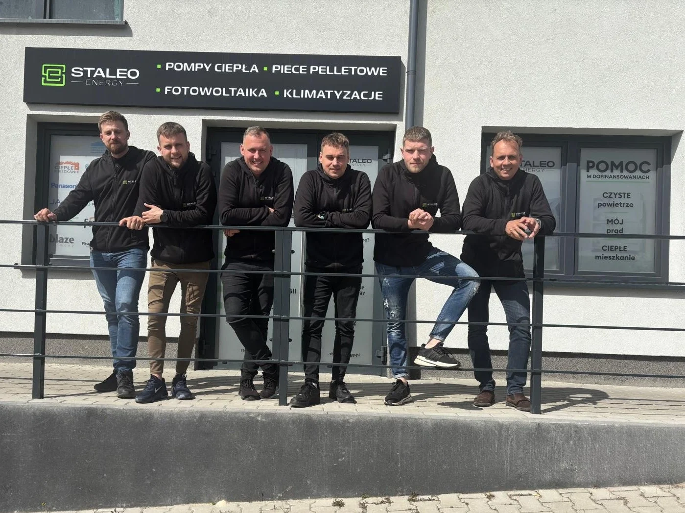 Zespół Staleo Energy stoi przed siedzibą firmy i pozuje do zdjęcia. Staleo Energy zajmuje się rozwiązaniami OZE dla firm i domów.